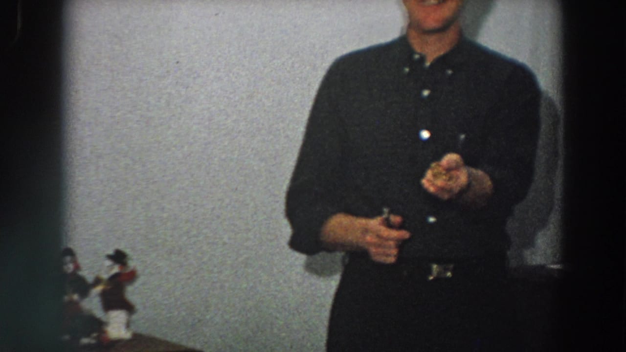 In a softly focused 1958 Italy interior, the man lifts one hand as if showing or inspecting a small item.