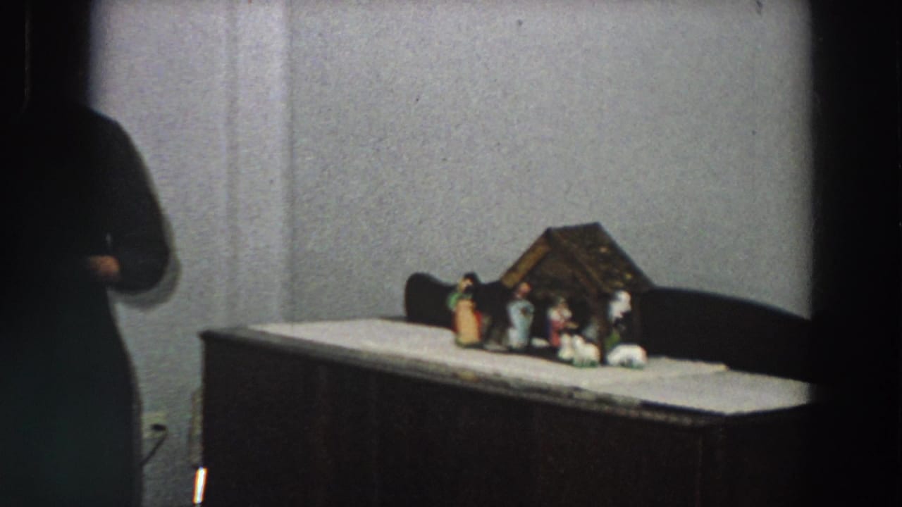 A small nativity arrangement with several figurines sits on a cabinet or table in a plain interior, shown in 1958 Italy home-movie footage.