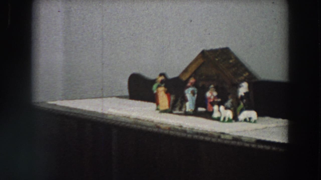 1958 Italy home-movie still showing a closer view of a small nativity scene on a white cloth-covered cabinet.
