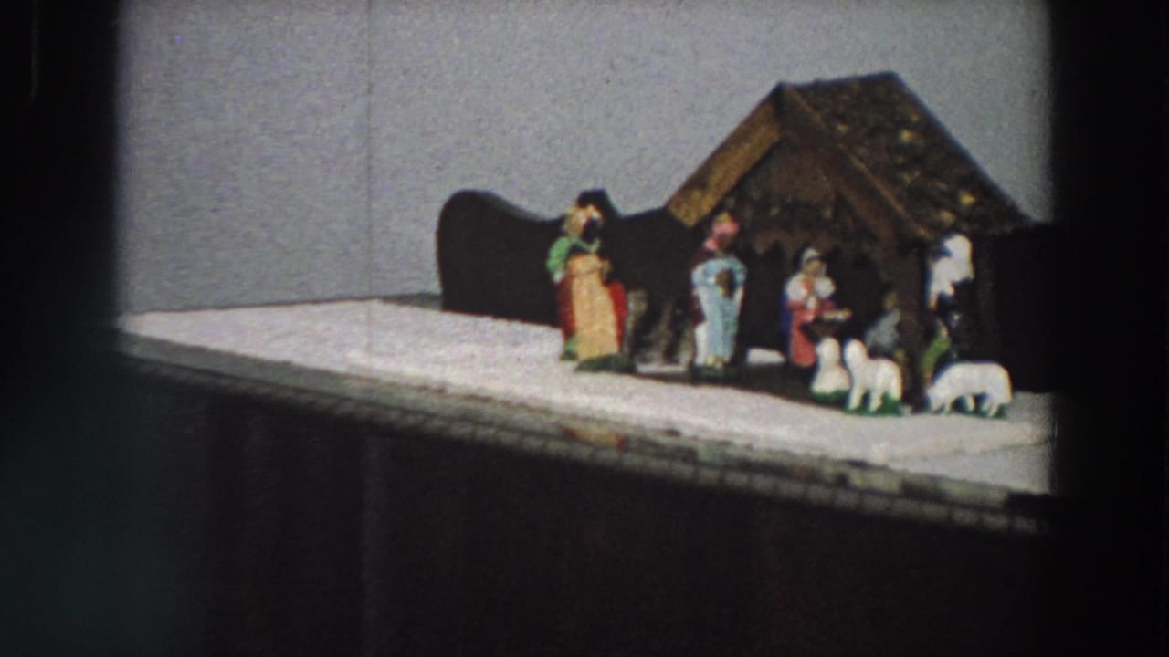1958 Italy frame showing a home Christmas nativity display with stable, figures, sheep and white cloth base.
