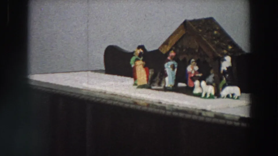 1958 Italy frame showing a home Christmas nativity display with stable, figures, sheep and white cloth base.