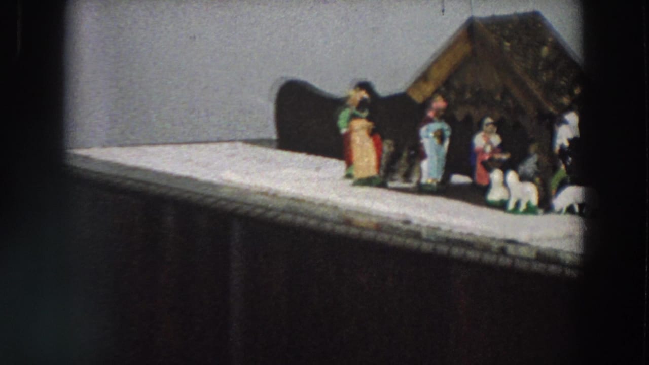 Small nativity figures and sheep stand in front of a miniature stable.
