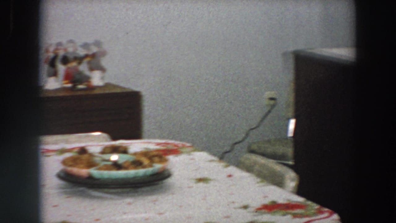 1958 Italy home interior with a dining table, platter, patterned tablecloth, wall outlet, and holiday decorations visible in the background.