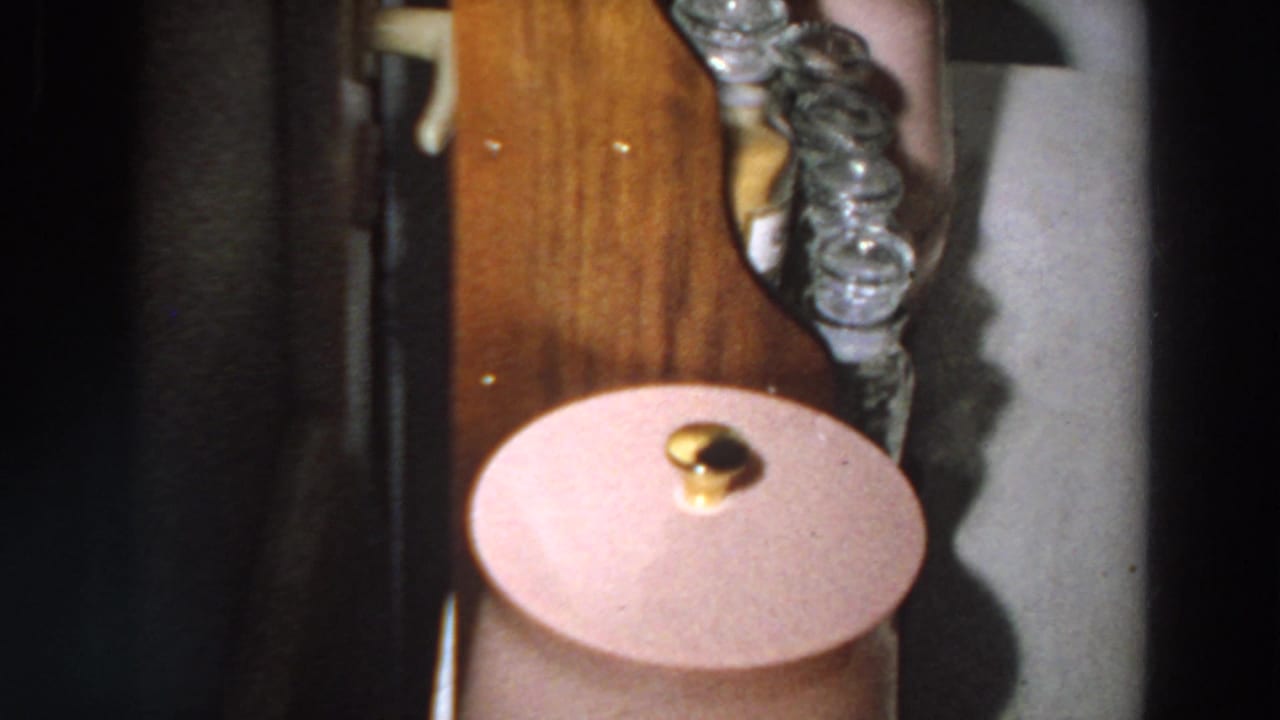 A wooden shelf in the Italian home holds clear glass jars and a pink lidded container, with the camera framed close in 8mm.