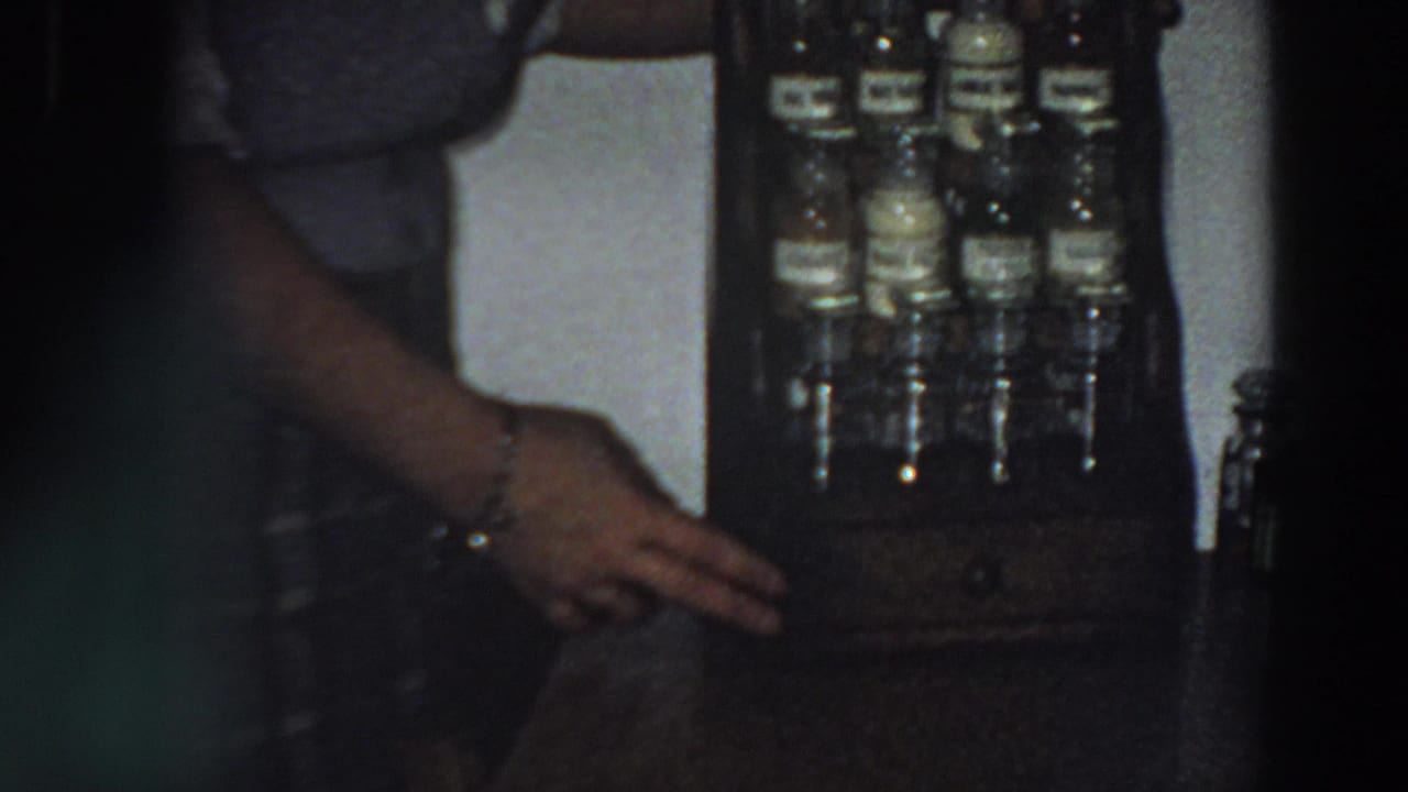 Close view of a hand near labeled bottles in a wooden holder.