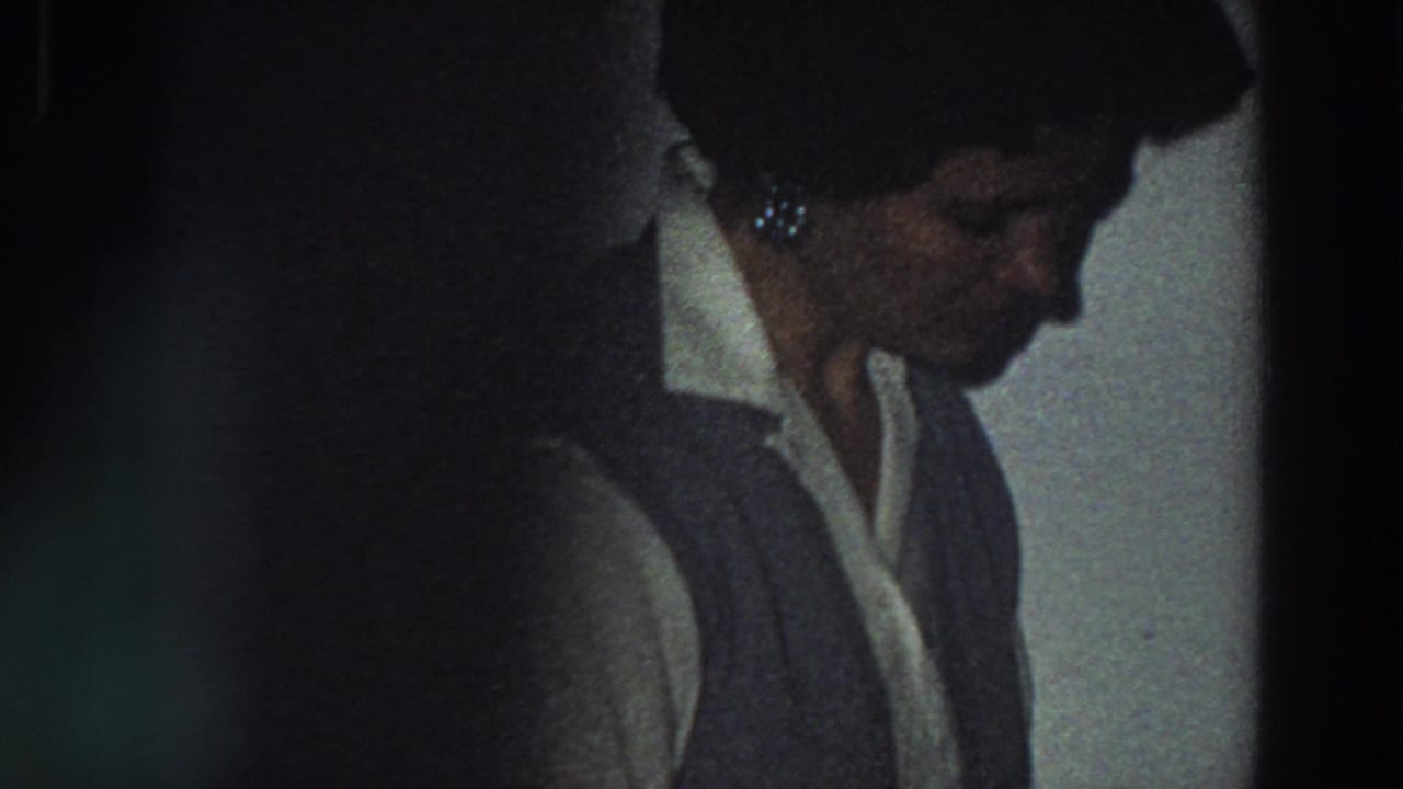 A woman in a white collared shirt and dark vest looks down in a dim private interior, consistent with the Italy 1958 metadata.