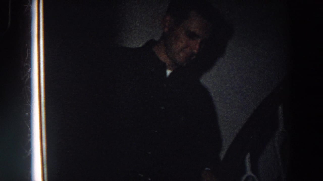 Near the end of the clip, the man's face is partly visible in shadow beside the stair rail in the dim interior.