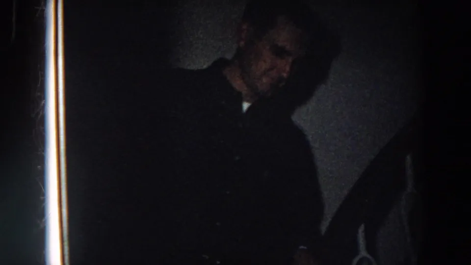 Near the end of the clip, the man's face is partly visible in shadow beside the stair rail in the dim interior.