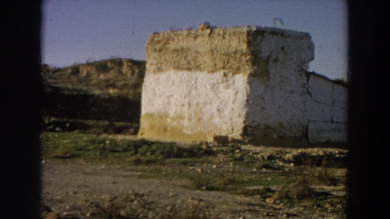 Whitewashed ruin wall in a sparse landscape under a clear sky.