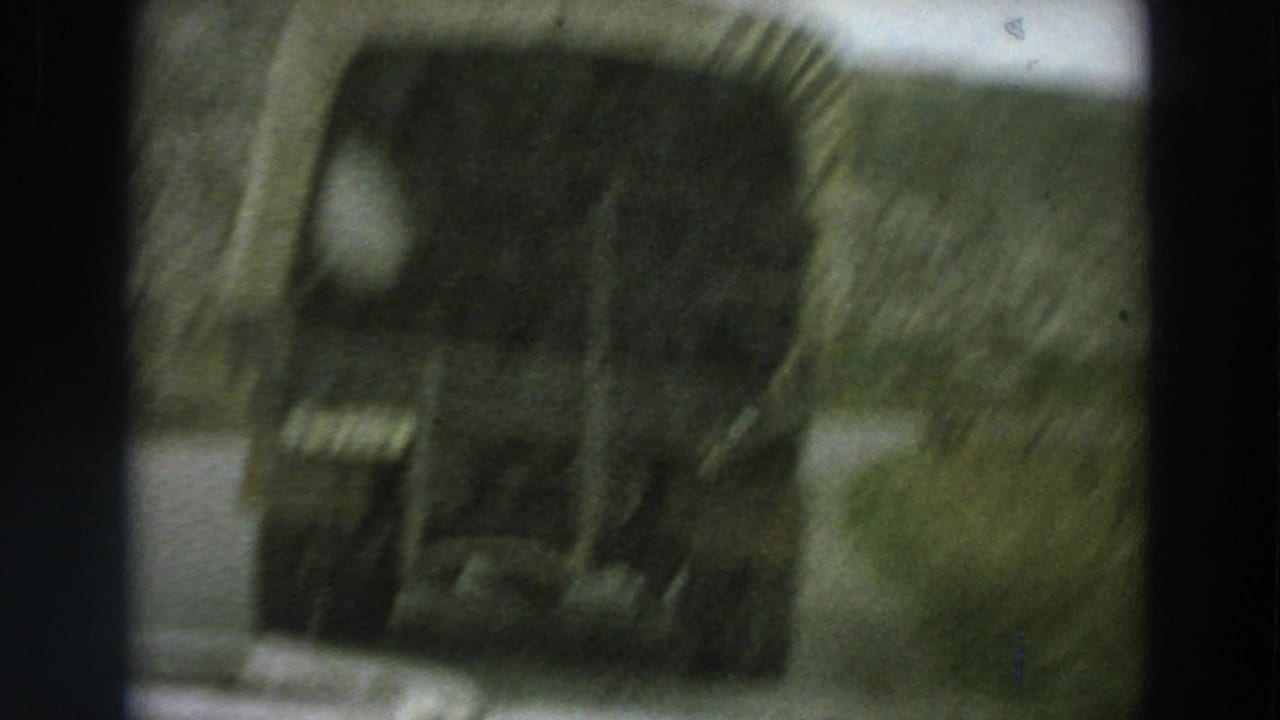 A close, blurred rear view of a canvas-covered truck fills the frame during a moving-car shot on an Italian country road.