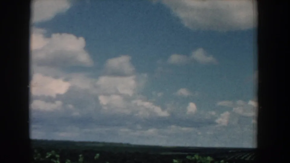 1958 South Carolina 8mm view of blue sky and white clouds over a distant rural treeline.