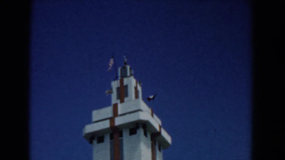 Low-angle 1958 South Carolina view of a white Art Deco-style tower or monument with small flags near the top.