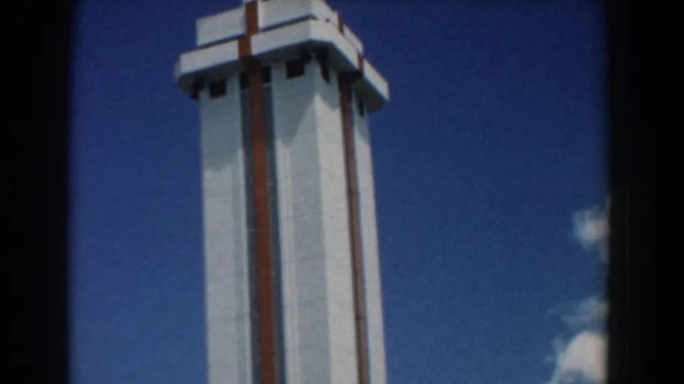 1958 South Carolina 8mm frame with the tower centered near a dark film divider, set against blue sky with small clouds.