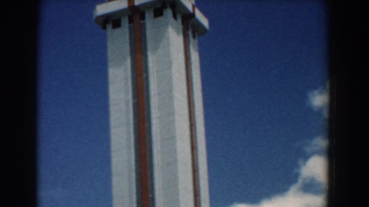 1958 South Carolina home-movie frame showing part of a tall white tower with red stripes under a blue sky.