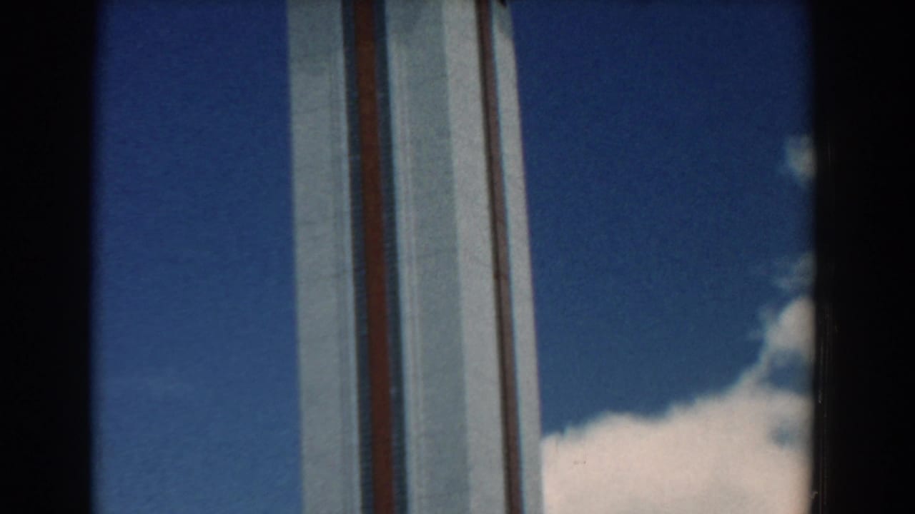 Tall white tower section with red stripes beside blue sky and cloud.