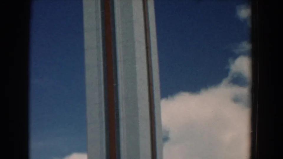 Final visible frame of the South Carolina tower, with its white face and red vertical accents set against sunlit clouds.