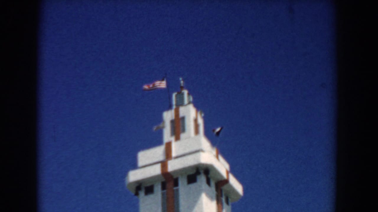 White decorative tower topped by an American flag against blue sky.