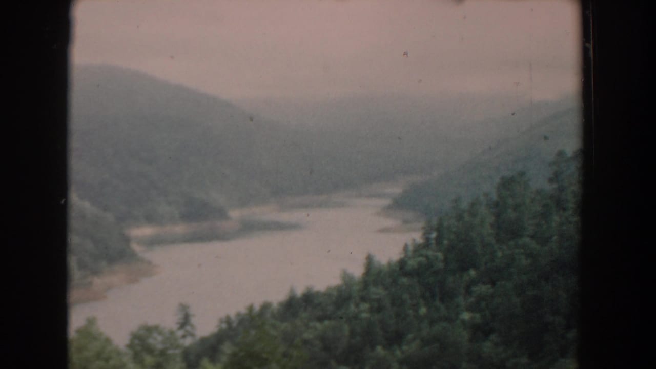 River curving into the distance between wooded hills.