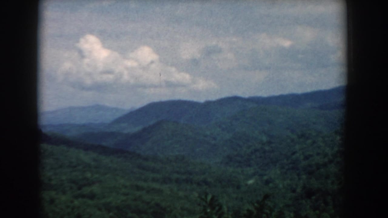Distant blue-green ridges and clouds seen through rounded dark film borders.