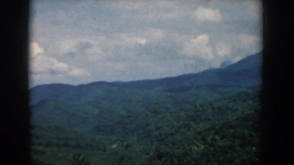 1958 South Carolina 8mm frame showing green mountain ridges and cloudy sky through dark frame or window-like borders.