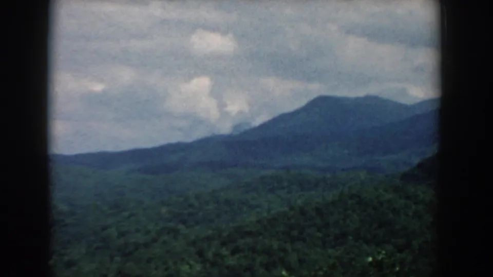 South Carolina 1958 8mm frame showing a rounded mountain ridge over dense green forest beneath a cloudy sky.