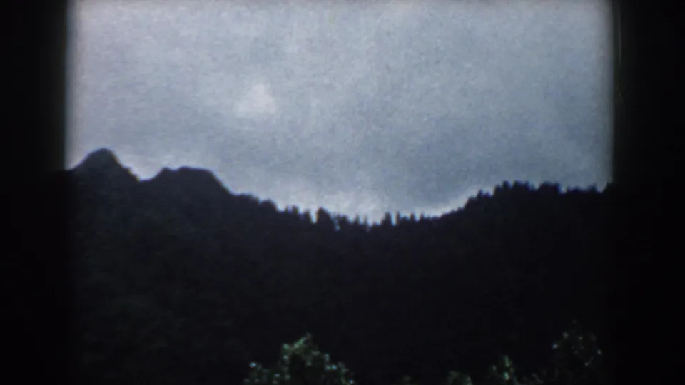 1958 South Carolina 8mm frame showing a silhouetted forested ridge below a heavy, clouded sky.