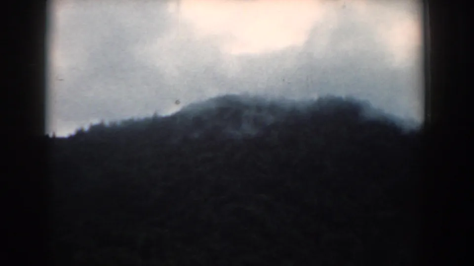 1958 South Carolina 8mm view of a distant forested mountain ridge under thick, pale clouds with dark frame borders.