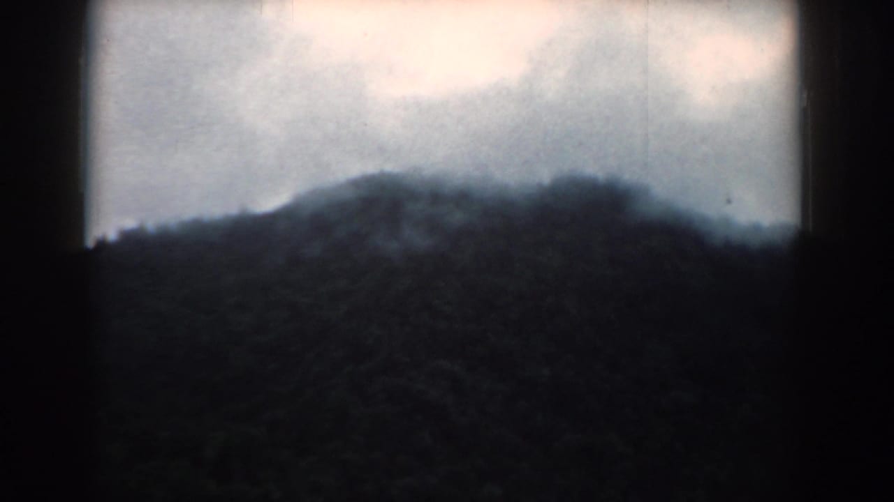 1958 South Carolina 8mm frame showing a soft, misty mountain ridge beneath a pale cloudy sky.