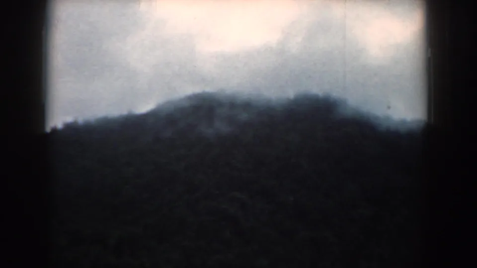 1958 South Carolina 8mm frame showing a soft, misty mountain ridge beneath a pale cloudy sky.