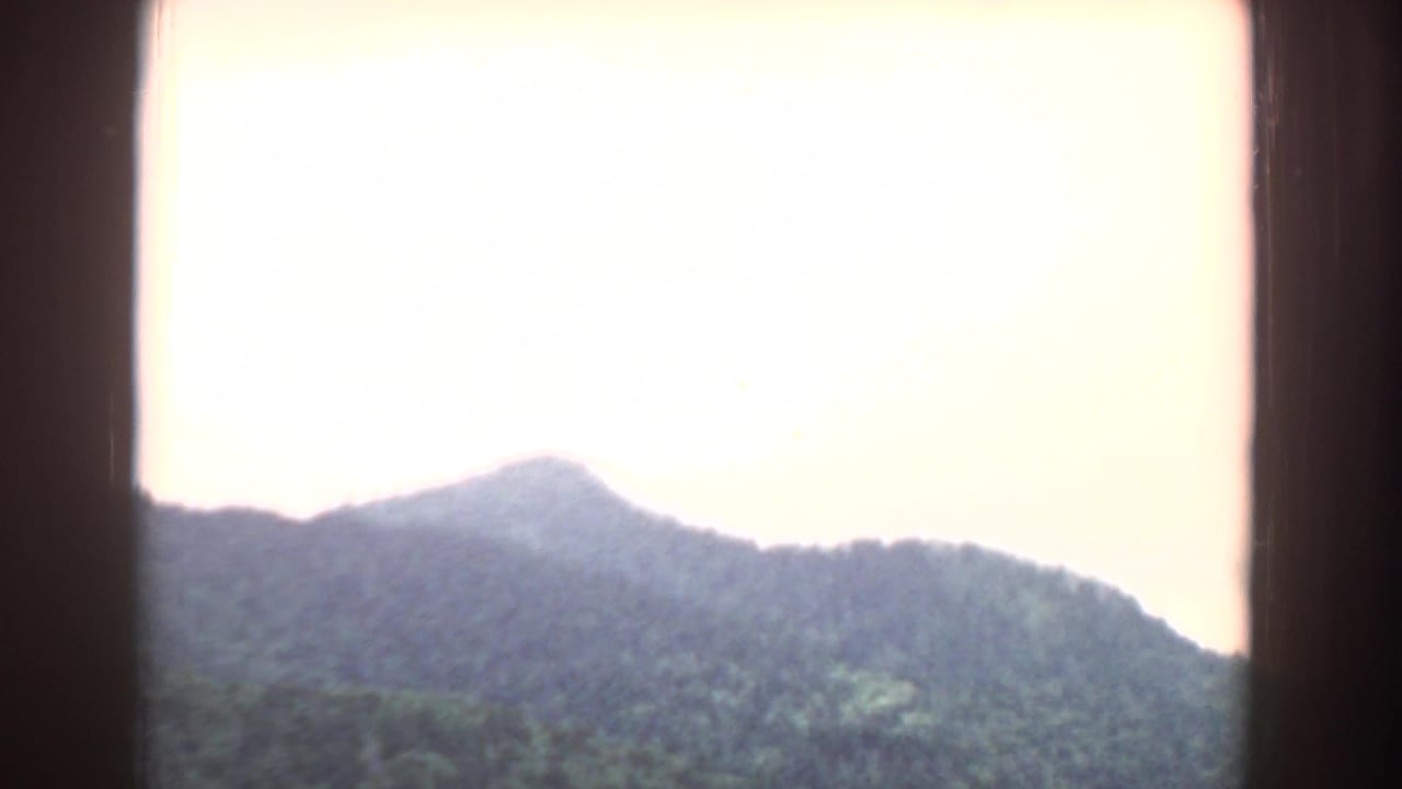 Mountain ridge seen through a dark window frame under bright sky.