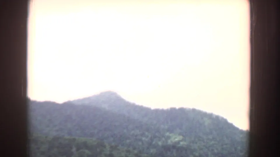 1958 South Carolina 8mm frame of a wooded mountain ridge viewed through a dark window frame beneath a washed-out sky.