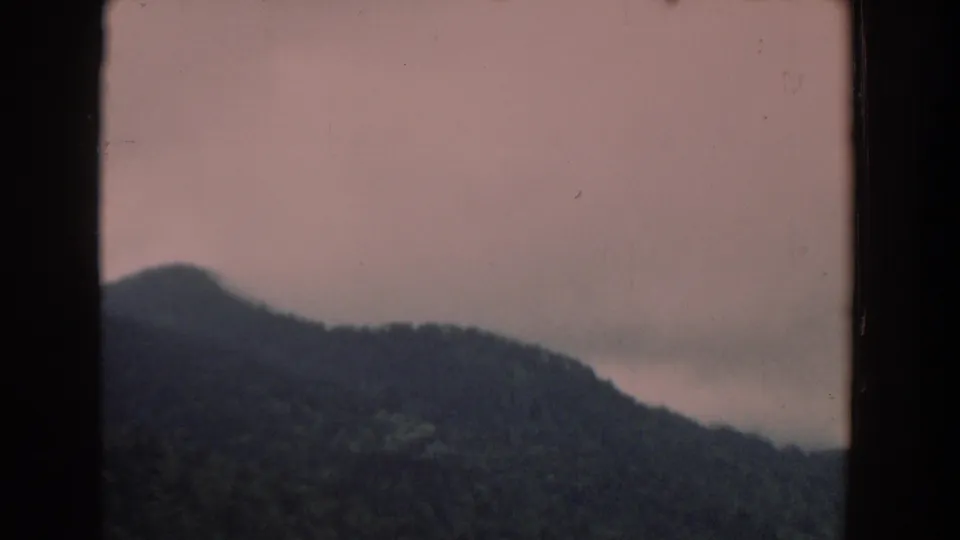 1958 South Carolina 8mm frame of a wooded mountain ridge fading into haze under a muted pink sky.
