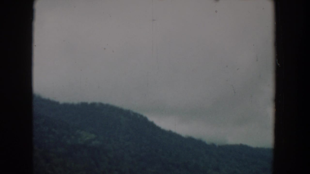 1958 South Carolina 8mm view of a forested ridge and low storm clouds, with visible film edges and muted color.