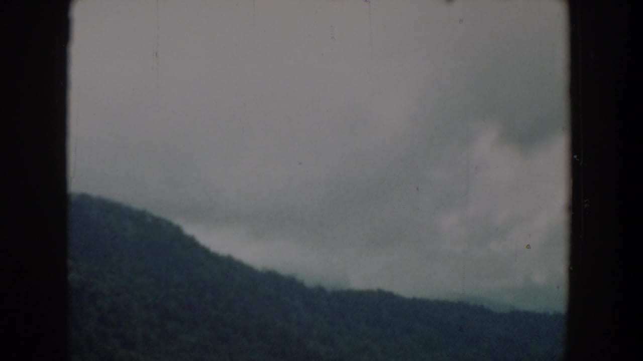 Wooded hills under a gray cloudy sky with dark 8mm frame borders.