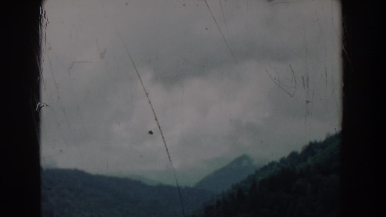 Cloudy mountain view with a central dark film divider.