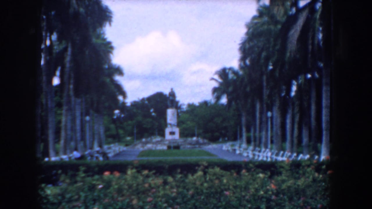 A South Carolina garden scene on 8mm film shows palms, benches, hedges, and a monument framed by dark foreground edges.