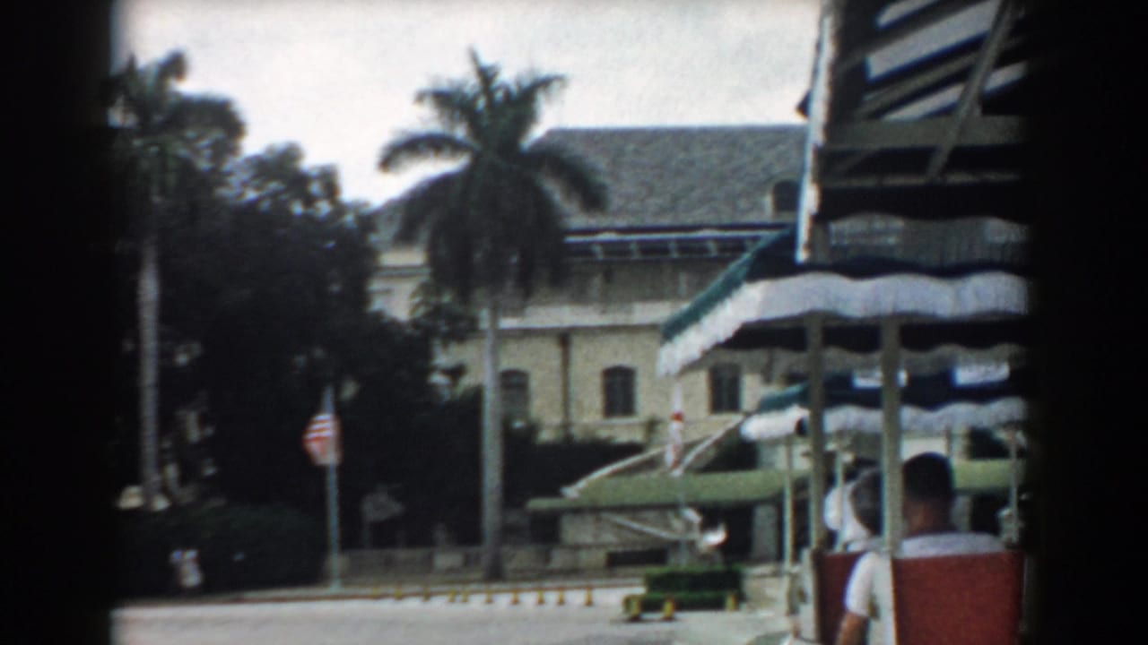 A passing 1958 South Carolina view shows the palm-lined building entrance, striped awnings, flag, and a seated passenger partly visible at right.