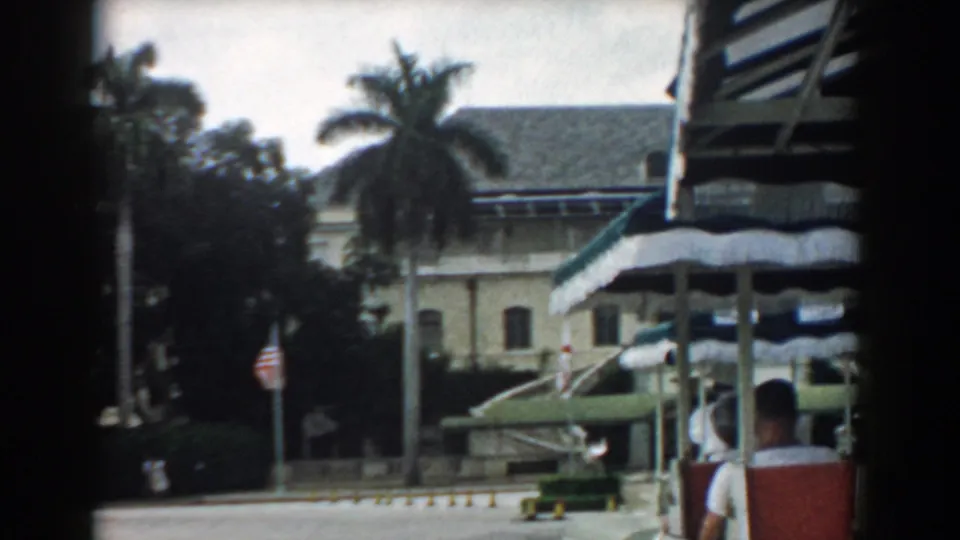 A passing 1958 South Carolina view shows the palm-lined building entrance, striped awnings, flag, and a seated passenger partly visible at right.