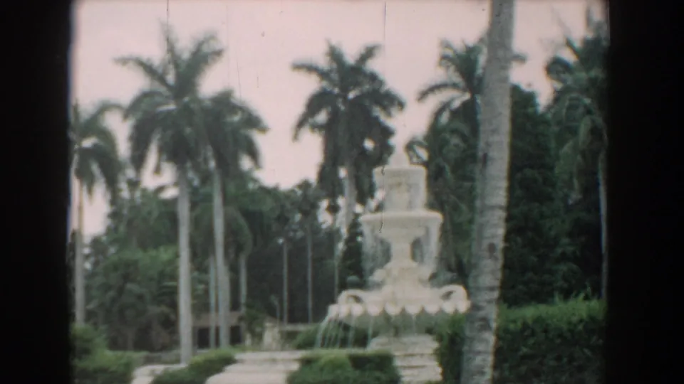1958 South Carolina frame showing a white fountain-like structure among palms, hedges, and landscaped garden grounds.