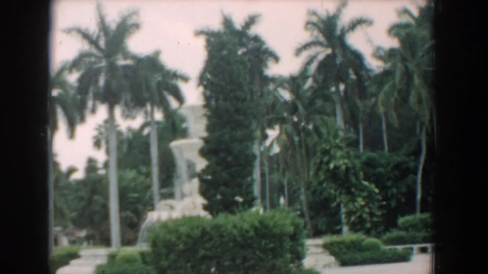 1958 South Carolina frame showing the fountain from farther right, with palm trees, clipped hedges, and visible 8mm frame borders.