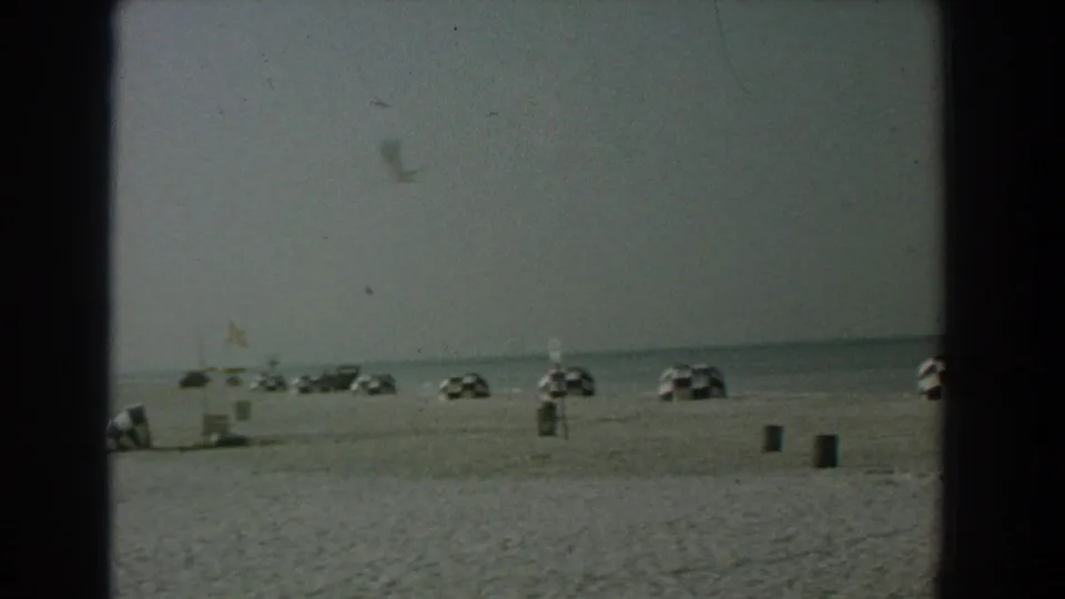 1958 Yorktown, Virginia beach view with checkered umbrellas spaced across sand and calm water on the horizon.