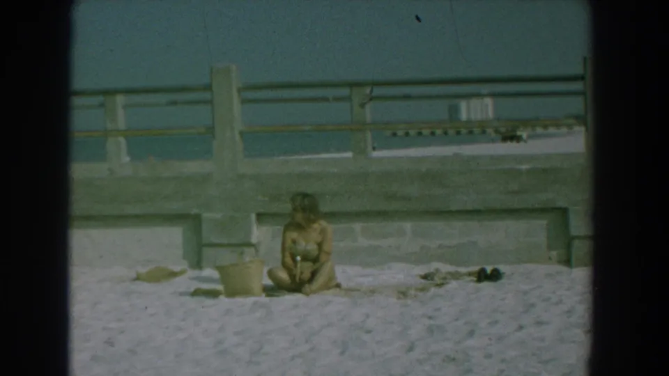 The final frame shows a woman seated on the sand near a seawall and railing, with a bucket and shoes visible beside her.
