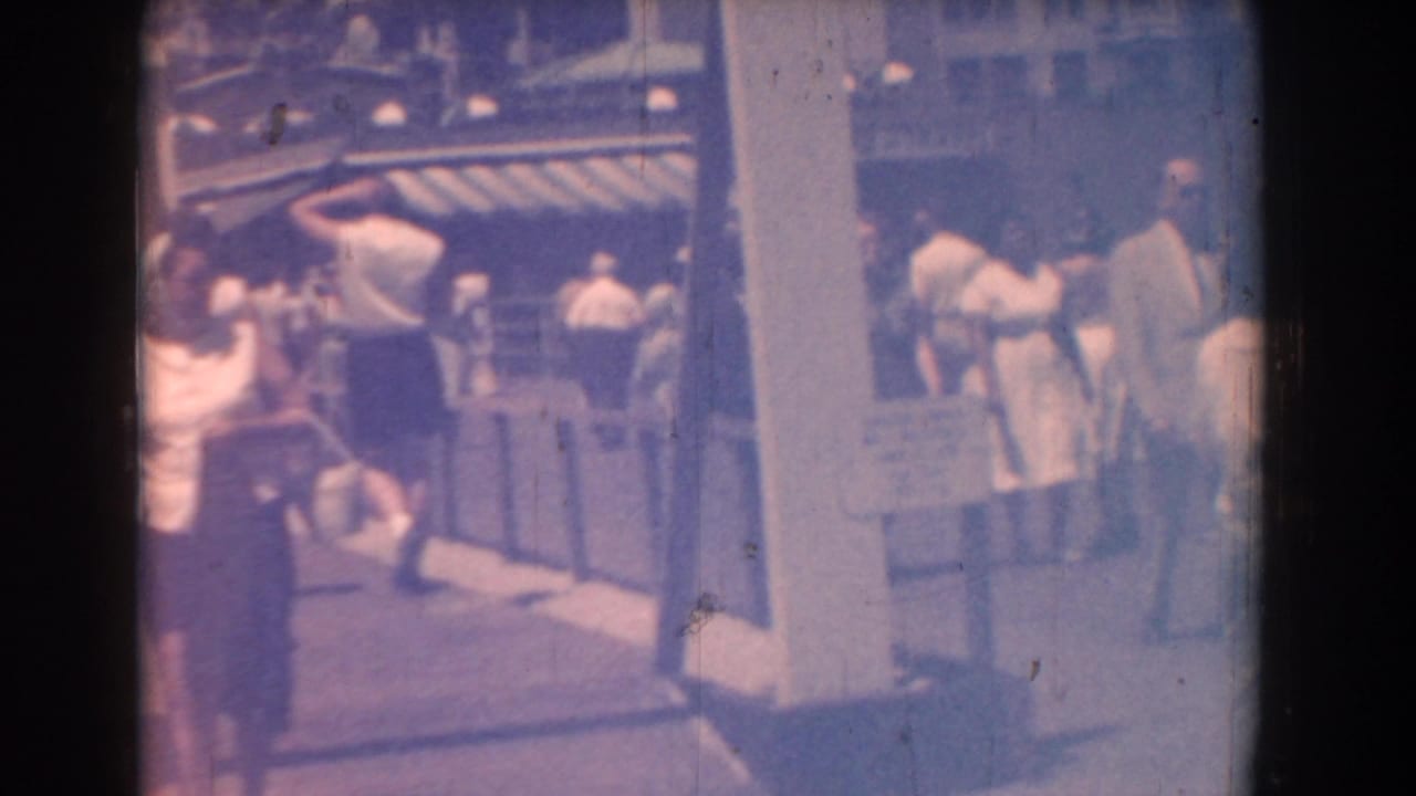 Boardwalk crowd at Yorktown in 1958, with adults in summer clothing moving past striped awnings and railings.