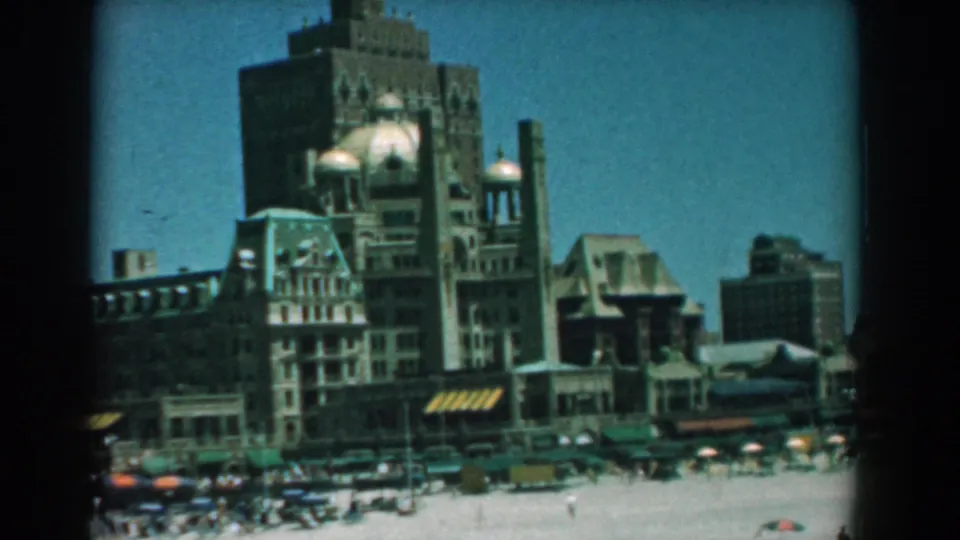 1958 Yorktown, Virginia frame with ornate multi-story waterfront buildings overlooking a busy sunlit beach.