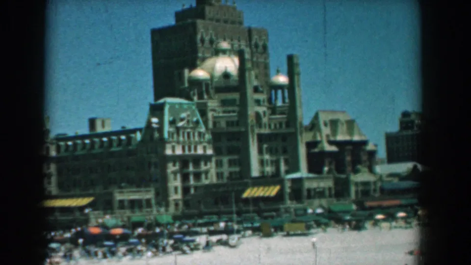 1958 Yorktown, Virginia home-movie view of tall waterfront architecture rising behind beachgoers and umbrellas.