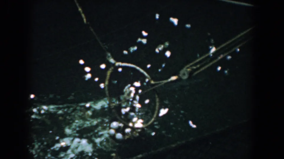 Close-up from the same Yorktown 1958 home movie showing fishing tackle or a net beside dark water with glints of light.