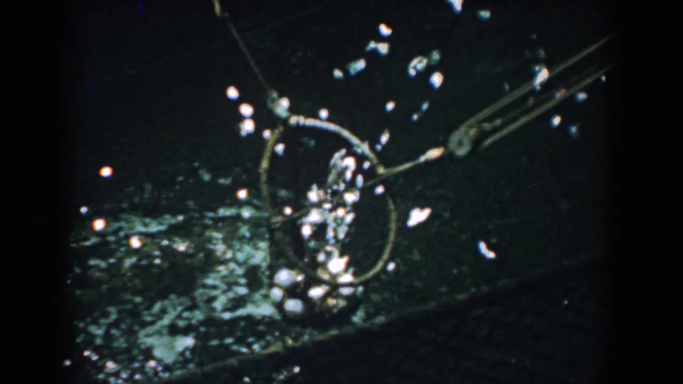 1958 Yorktown 8mm frame showing a circular fishing net rising through dark water with reflective splashes and angled metal arms.