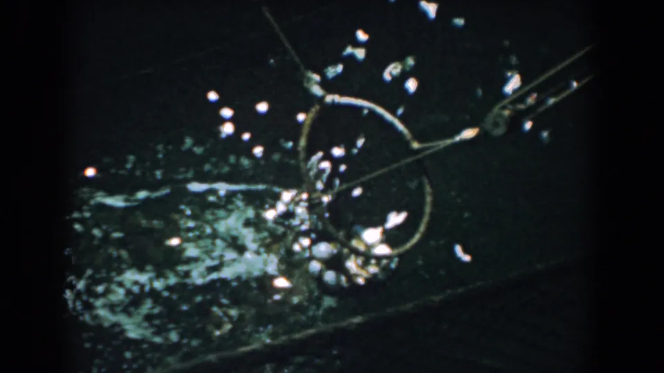1958 Yorktown 8mm frame with the round net partly raised, water rippling around the catch and mechanical arm.