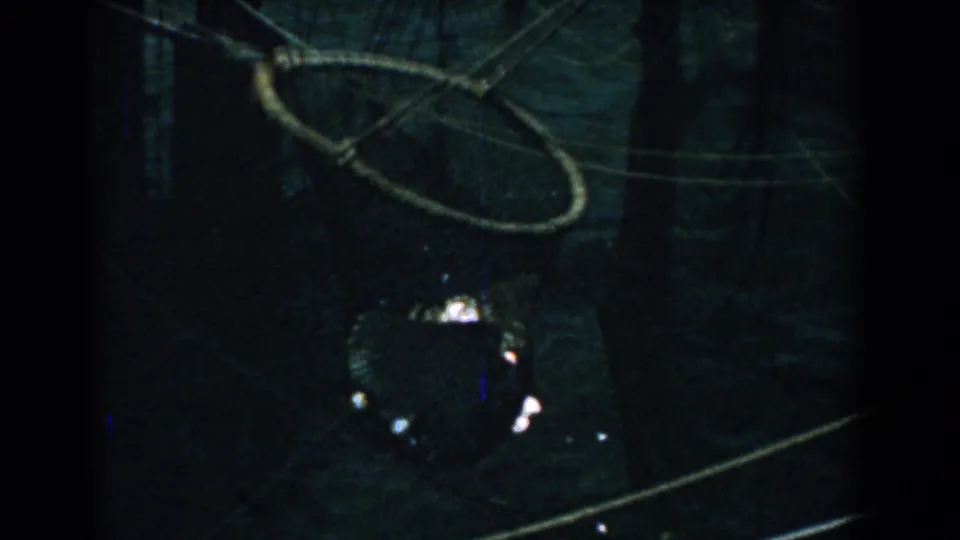 1958 Yorktown 8mm frame showing the circular net raised in dim light, with catch below and dark waterfront surroundings.