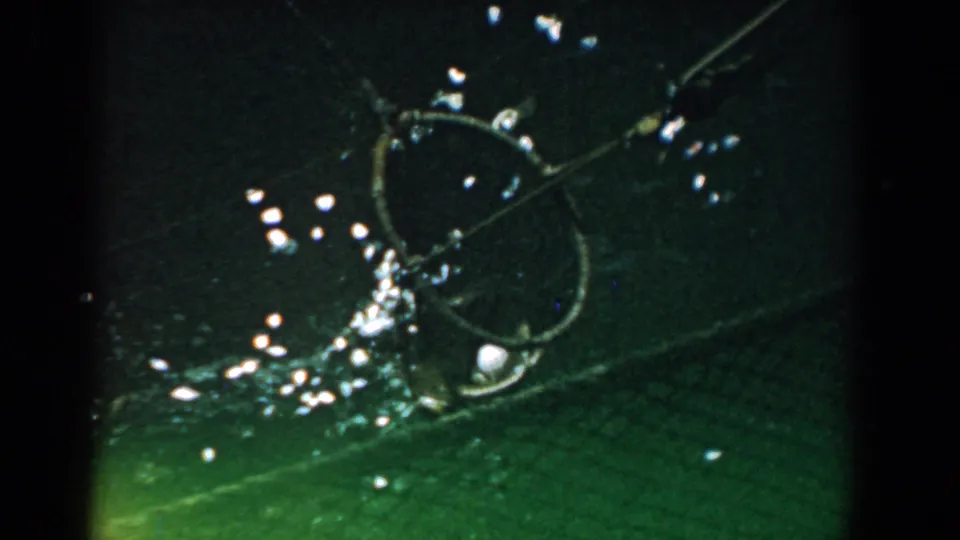 Late frame from the 1958 Yorktown clip, with a green-tinted close-up of a circular metal shape and bright reflected specks.